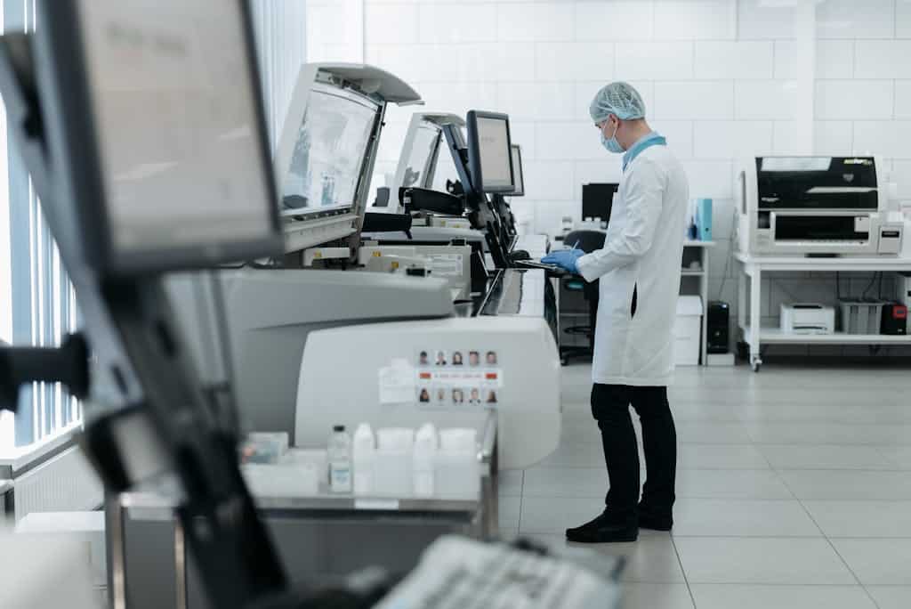 A scientist in a lab coat using advanced laboratory equipment in a clean, modern lab.