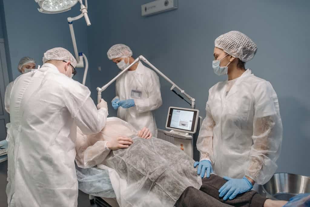 Healthcare professionals conducting a laser surgical procedure in a clinic setting.